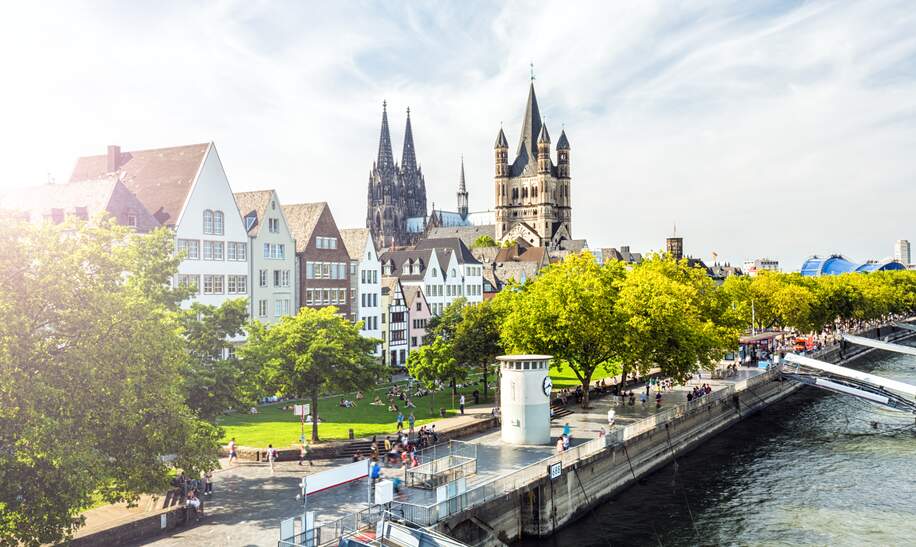 Menschen laufen auf der Rheinpromenade in Köln, der Blick auf die Kölner Altstadt | © Gettyimages.com/querbeet