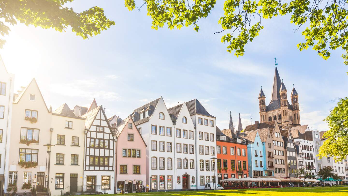 Bunte Häuser und ein Park in Köln. der Kirchturm im Hintergrund.  | © Gettyimages.com/jotily