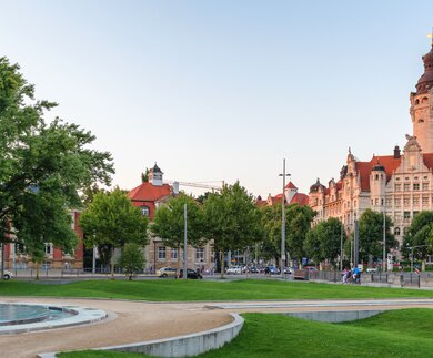 Stadtpark in Leipzig mit einem großen Brunnen im Vordergrund und Rathaus | © gettyimages.com/tichr