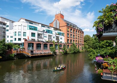 Fluss Elster, auf dem ein Boot fährt, im Szenedistrikt Schleussig mit schönen Loft in alten Industriegebäuden in Leipzig | © Gettyimages.com/kamisoka