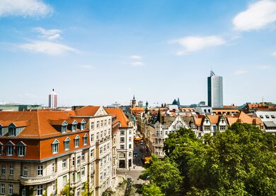 Aufnahme von Leipzig über die Dächer der Stadt an einem sonnigen Tag. Auf der Straßen laufen Passanten.  | © Gettyimages.com/TommL