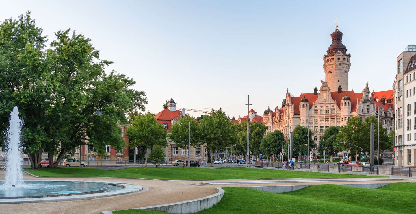 Stadtpark in Leipzig mit einem großen Brunnen im Vordergrund und Rathaus | © gettyimages.com/tichr
