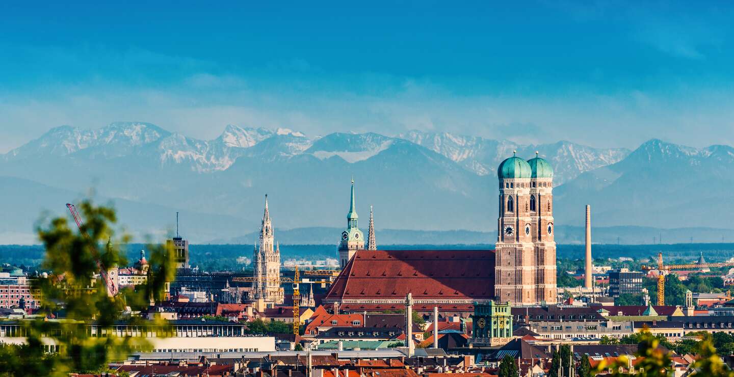 Die Skyline von München mit der Frauenkriche bei schönem Wetter mit Bergen im Hintergrund | © Gettyimages.com/jotily