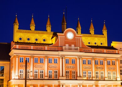 Blick auf das Rathaus in Rostock, welches bei Nacht beleuchtet ist | © Gettyimages.com/benkrut
