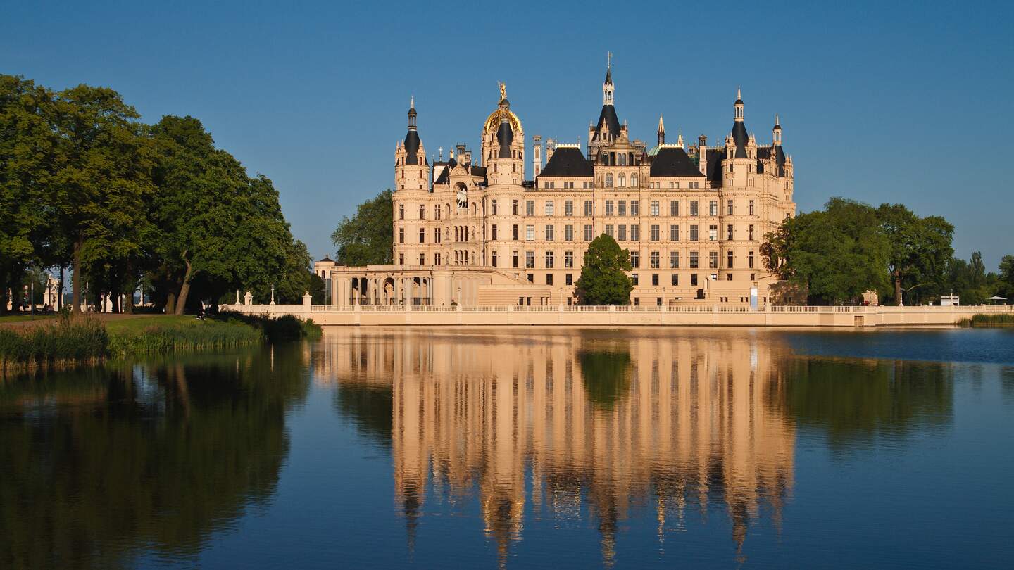  Schloss mit vielen Tuermen und Verzierungen, das sich malerisch im ruhigen Wasser spiegelt. | © gettyImages.com/RicoK69