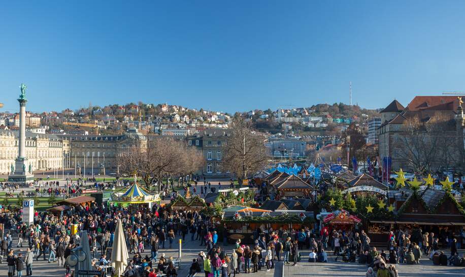 Auf dem Weihnachtsmarkt in Stuttgart stehen viele Besucher an einem sonnigen Tag.  | © Gettyimages.com/S_A_N