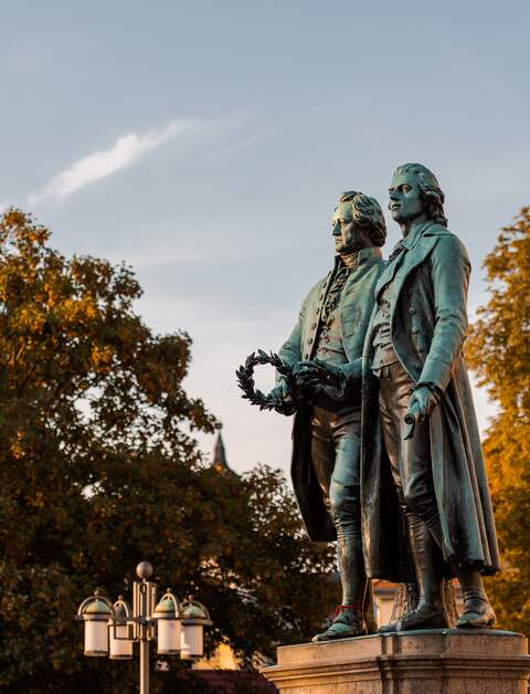 Goethe-Schiller-Denkmal in Weimar im Sonnenlicht am Morgen unter blauem Himmel | © © Gettyimages.com/Robert Ruidl