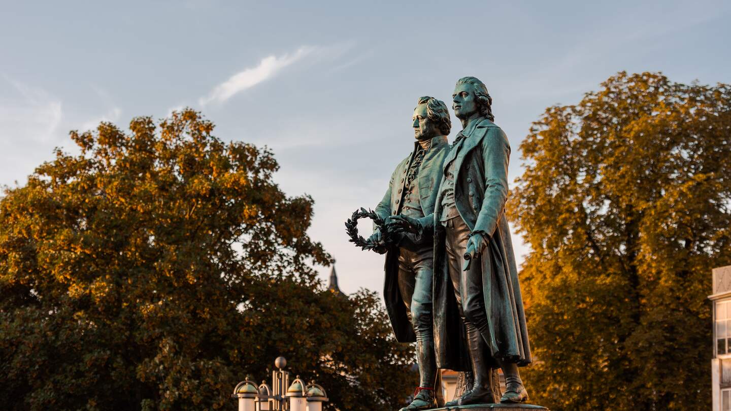 Goethe-Schiller-Denkmal in Weimar im Sonnenlicht am Morgen unter blauem Himmel | © Gettyimages.com/Robert Ruidl