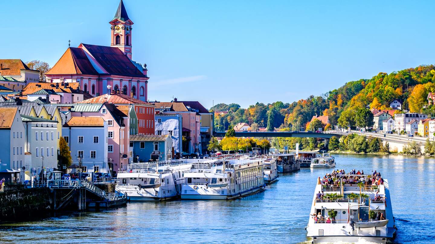 Ein Ausflugsboot mit Touristen an Bord fährt auf dem Fluss in Passau. Die Altstadt ist im Hintergrund. | © © Gettyimages.com/FooTToo