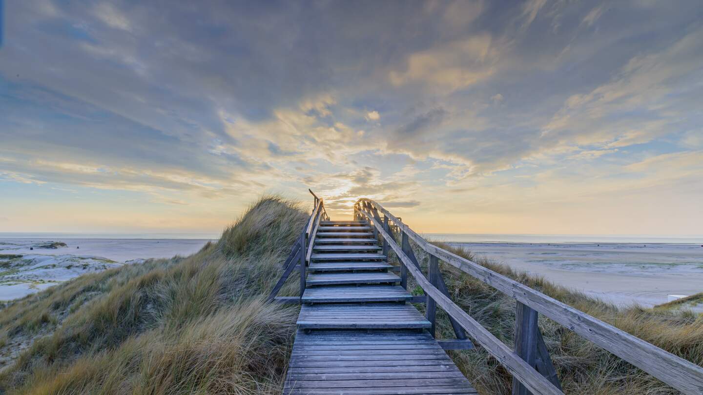 Steg und Treppe in den Duenen bei Sonnenuntergang, Norddorf, Amrum, Schleswig-Holstein | © Gettyimages.com/Frederick Doerschem