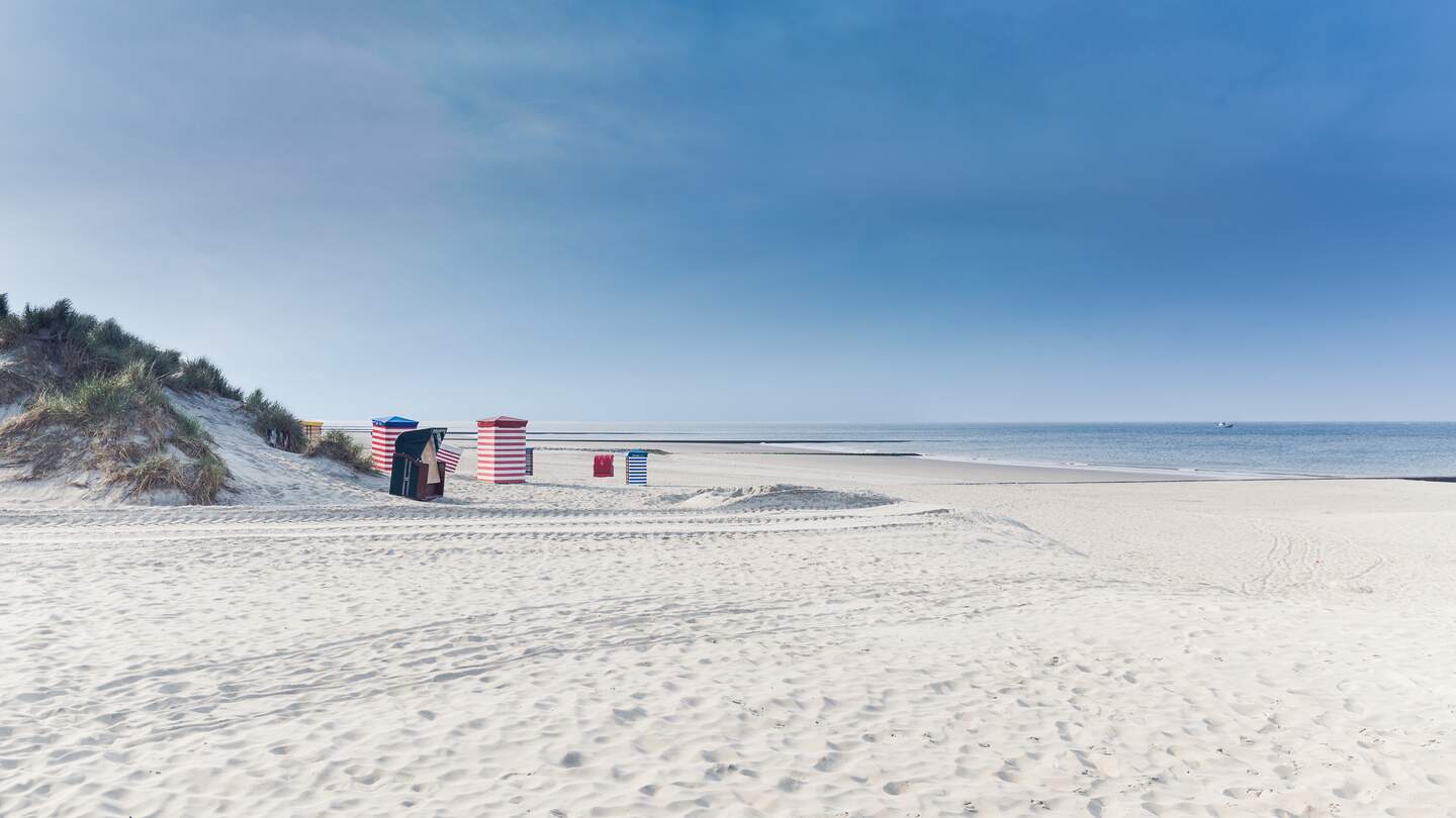 Strandkörbe auf der Insel Borkum mit weißem Sand und ein blauer Himmel | © Gettyimages.com/tobiasschwarz
