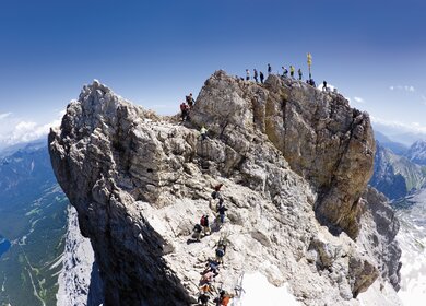 Eine Gruppe von Wanderern, die auf einem großen Felsen auf der Zugspitze stehen.  | © Gettyimages.com/Westend 61