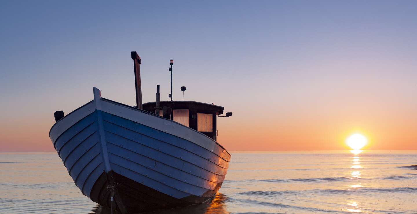 Typisches Fischerboot an der Ostsee im Sonnenuntergang am Strand