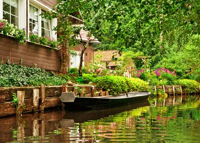 Kleine Ferienhaeuser in der Naehe der Spree mit einem Boot auf dem Fluss | © Gettyimages.com/kerrick