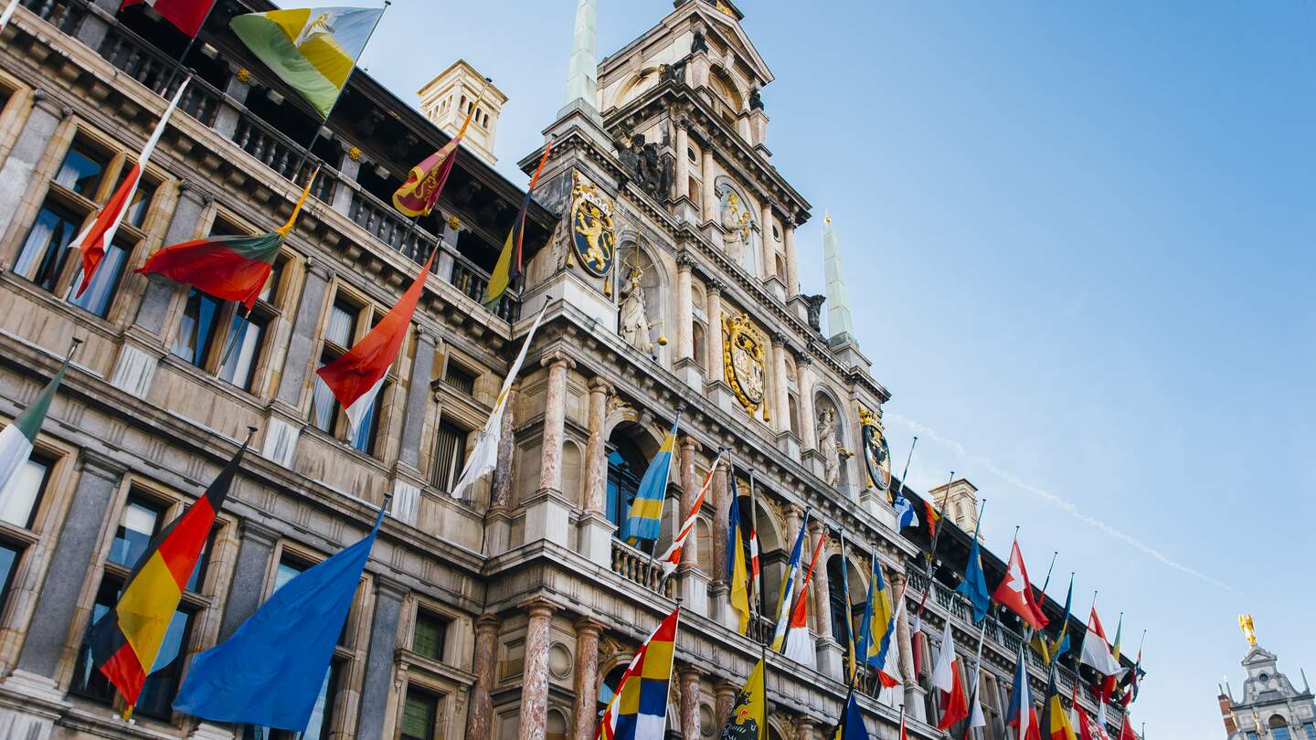 Blick über die historische, geflaggte Fassade des Rathauses von Antwerpen gen blauem Himmel in Antwerpen, Flandern/Belgien | © Gettyimages.com/MarioGuti
