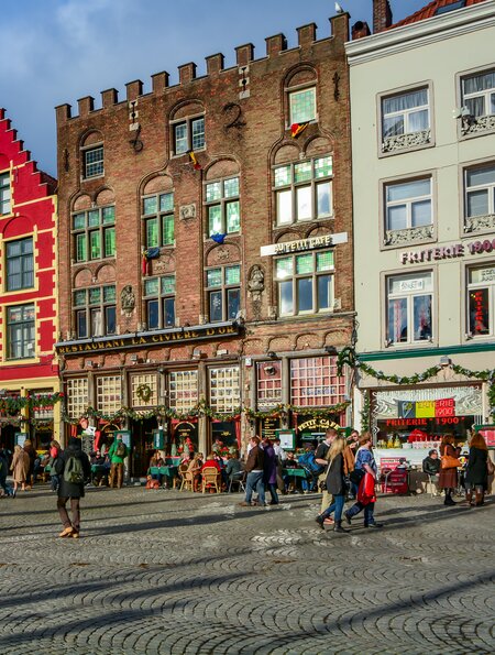 Gebäude im mittelalterlichen Stil in der Nähe des Marktplatzes (Grote Markt) in Brügge. Menschen flanieren auf dem Platz. | © Gettyimages.com/HIT1912
