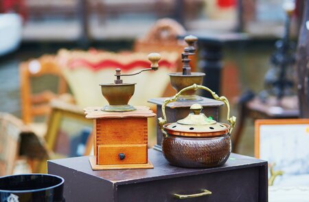 Auf einem Flohmarkt in Bruegge stehen Antiquitäten wie eine alte Kaffeemuehle und eine Teekanne.  | © Gettyimages.com/encrier