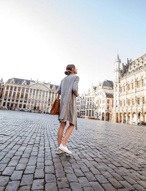 Junge Frau, die auf dem Hauptplatz mit Rathaus in der Altstadt von Bruessel spazieren geht | © Gettyimages.com/RossHelen