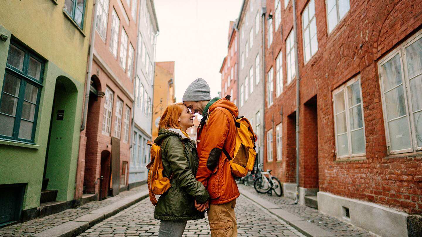 Paar steht verliebt, Stirn an Stirn, in der mitte einer Strasse in Kopenhagen mit bunten Haeusern | ©  Gettyimages.com/alesksandernakic