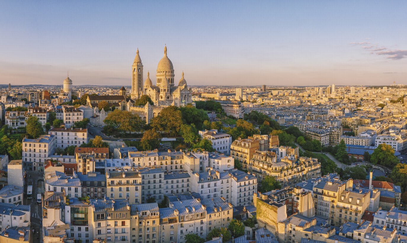 Luftaufnahme des Montmartre-Hügels mit der Basilique du Sacre-Coeur in Paris bei Sonnenuntergang | © Gettyimages.com/pawel.gaul