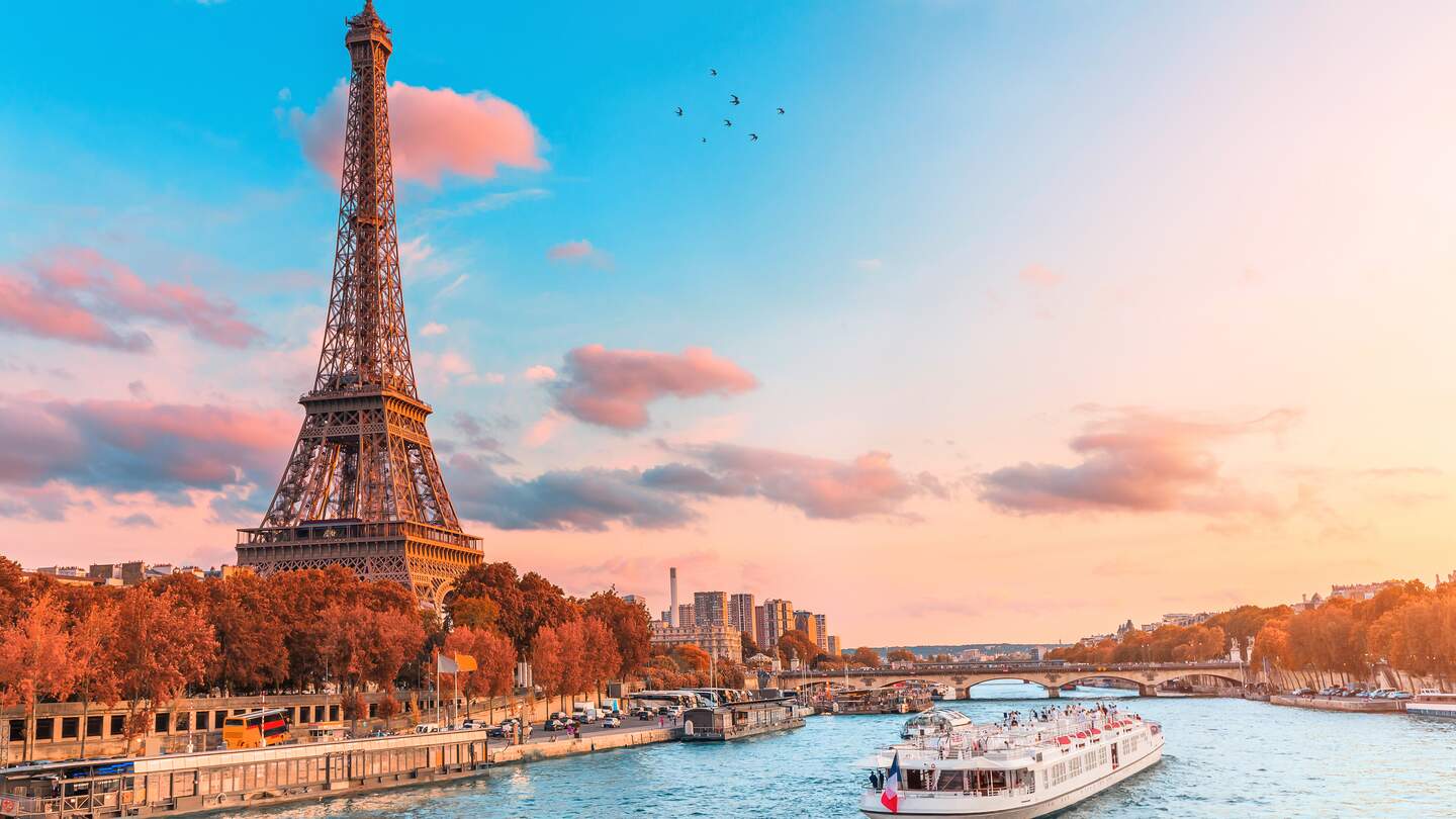 Bootstour in den Strahlen der untergehenden Sonne am Ufer der Seine mit Kreuzfahrtschiffen vor dem Eiffelturm | © Gettyimages.com/frantic00