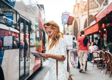 Schöne, junge Frau in Paris macht eine Bustour, eine Stadtkarte in der Hand haltend  | © Gettyimages.com/Jasmina007