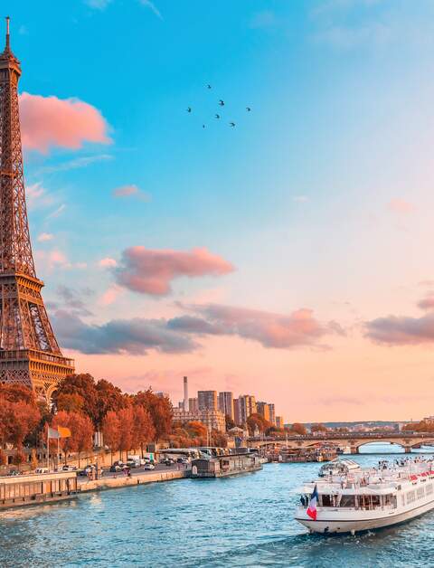 Bootstour in den Strahlen der untergehenden Sonne am Ufer der Seine mit Kreuzfahrtschiffen vor dem Eiffelturm | © Gettyimages.com/frantic00