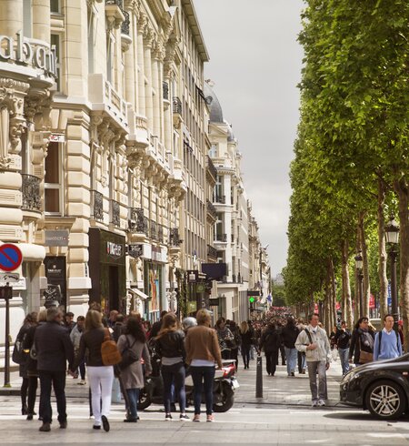 Passanten gehen auf der Avenue des Champs-Élysées in Paris shoppen . | © Gettyimages.com/MediaProduction