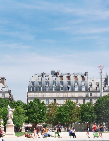 Menschen sitzen im Jardin des Tuileries an einem Sommertag in Paris, rechts ein Brunnen und ein Riesenrad | © Gettyimages.com/neirfy