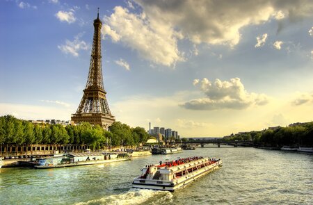 Menschen machen eine Bootsfahrt auf der Seine in Paris, Lastkähne und Bäume bei Sonnenuntergang. | © Gettyimages.com/AleksandarGeorgiev