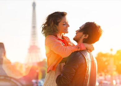 Verliebtes Paar hält sich in Paris im Arm mit dem Eiffelturm und Sonnenstrahlen im Hintergrund | © Gettyimages.com/Sylvain SONNET