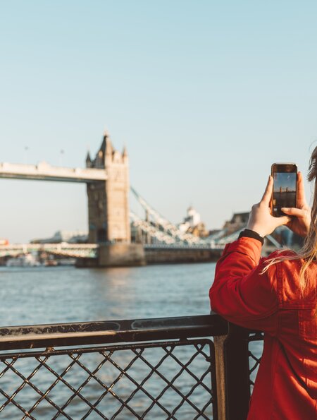 Touristin auf Städtereise erkundet die bekanntesten Sehenswürdigkeiten Londons – mit der Tower Bridge im Hintergrund. | © Gettyimages.com/Ziga Plahutar