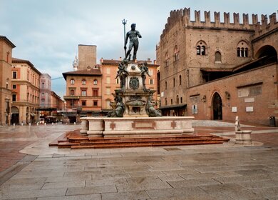 Blick auf den Neptunbrunnen auf der Piazza Maggiore in Bologna mit bewoelktem Himmel | © Gettyimages.com/treeffe