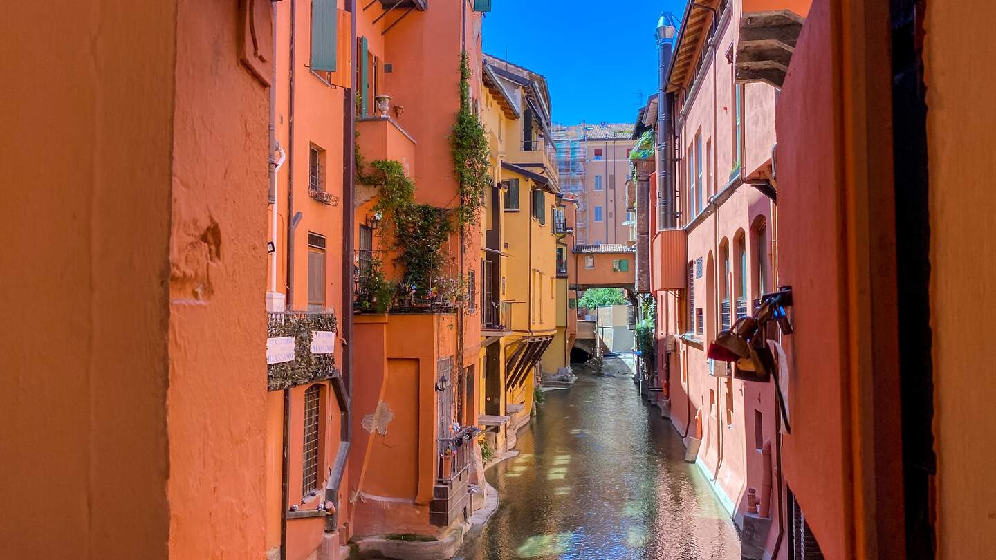 Blick auf einen kleinen Kanal in Bologna durch ein rot umrahmtes Fenster | © Gettyimages.com/todamo