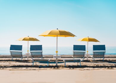 Typisches Strandbild mit blauen Liegen und gelben Sonnenschirmen am Strand von Ravenna an der Adria | © gettyimages.com/mdworschak