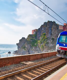 Erster Ausblick vom Bahnhof in Manarola, Cinque Terre, auf das malerische Dorf mit seinen bunten Häusern, das an der Klippe thront, mit dem Ligurischen Meer im Hintergrund. | © Gettyimages.com/Elijah-Lovkoff