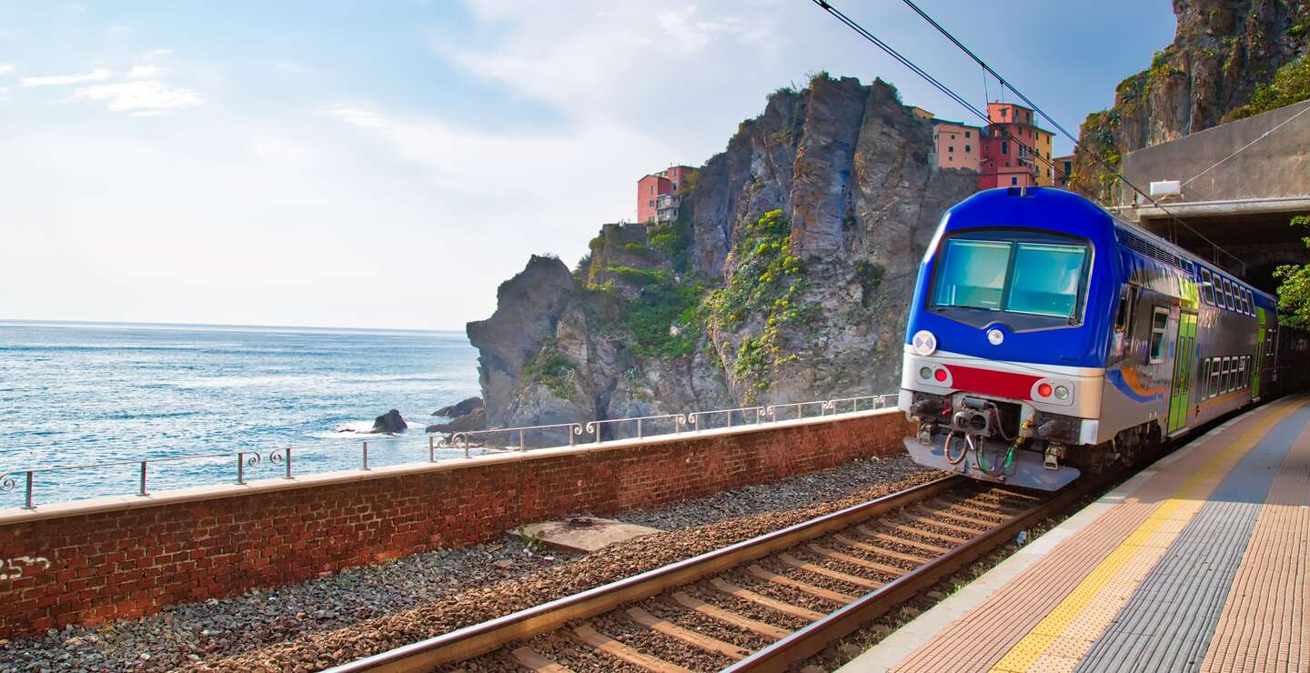 Erster Ausblick vom Bahnhof in Manarola, Cinque Terre, auf das malerische Dorf mit seinen bunten Häusern, das an der Klippe thront, mit dem Ligurischen Meer im Hintergrund. | © Gettyimages.com/Elijah-Lovkoff