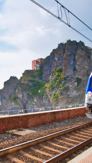 Erster Ausblick vom Bahnhof in Manarola, Cinque Terre, auf das malerische Dorf mit seinen bunten Häusern, das an der Klippe thront, mit dem Ligurischen Meer im Hintergrund. | © Gettyimages.com/Elijah-Lovkoff