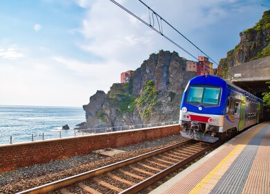Erster Ausblick vom Bahnhof in Manarola, Cinque Terre, auf das malerische Dorf mit seinen bunten Häusern, das an der Klippe thront, mit dem Ligurischen Meer im Hintergrund. | © Gettyimages.com/Elijah-Lovkoff