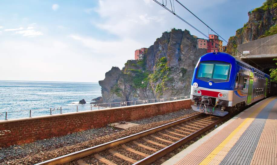 Erster Ausblick vom Bahnhof in Manarola, Cinque Terre, auf das malerische Dorf mit seinen bunten Häusern, das an der Klippe thront, mit dem Ligurischen Meer im Hintergrund. | © Gettyimages.com/Elijah-Lovkoff
