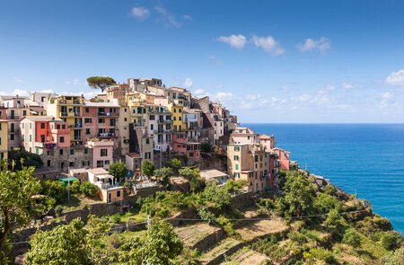 Corniglia, das malerische Dorf der Cinque Terre, thront auf hohen Felsen über dem Ligurischen Meer, während die Sonne die bunten Häuser zum Leuchten bringt. | © Gettyimages.vom/samvaltenbergs