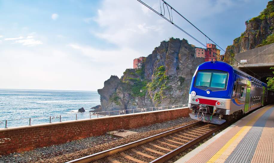 Erster Ausblick vom Bahnhof in Manarola, Cinque Terre, auf das malerische Dorf mit seinen bunten Häusern, das an der Klippe thront, mit dem Ligurischen Meer im Hintergrund. | © Gettyimages.com/Elijah-Lovkoff