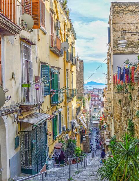Typische Strasse der Altstadt von Neapel: eng, steil, delapidatiert, malerisch, mit Jalousien an Fenstern, Blumentoepfen und trocknender Waesche | © Gettyimages.com/Avsinn