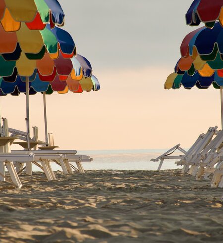Farbenfrohe Sonnenschirme am feinen Sandstrand von Rimini während des Sonnenuntergangs sorgen für entspannende Urlaubsatmosphäre | © Gettyimages.com/Giorgio Pasini