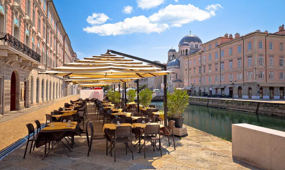 Kaffeehaus in der Altstadt von Triest Italien mit Ausblick auf die Kirche San Spiridione und historische Gebäude am Kanal | © Gettyimages.com/xbrchx