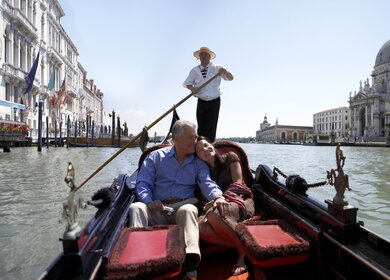 Glueckliches Paar, das an einem sonnigen Tag in einer Gondel auf dem Canal Grande sitzt. | © Gettyimages.com/Getty Images