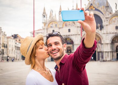 Schoenes, junges Paar, das ein Selfie vor dem Markusdom in Venedig macht.  | © Gettyimages.com/Diamond Dogs