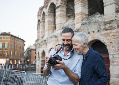 Verona, Italien | © Gettyimages.com/Vesnaandjic Mann und Frau in Verona, der Mann trägt eine Kamera um den Hals und sie schaut mit ihm darauf | © Gettyimages.com/Vesnaandjic