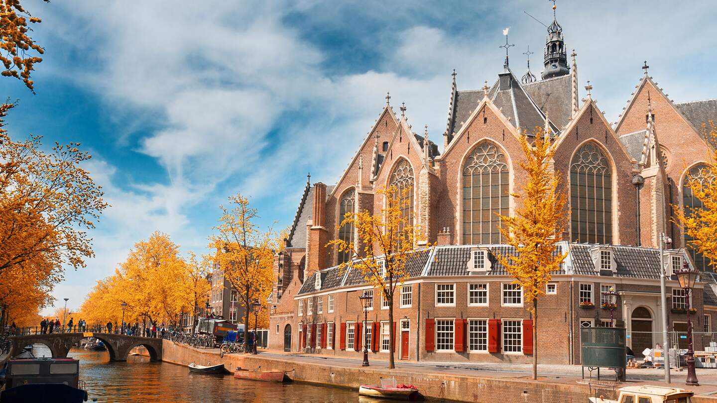 Ansicht von Amsterdam mit einem grossen, traditionellen niederlaendischen Gebaeude, das eine markante Treppengiebel und gewoelbte Fenster aufweist | ©  Gettyimages.com/neirfy