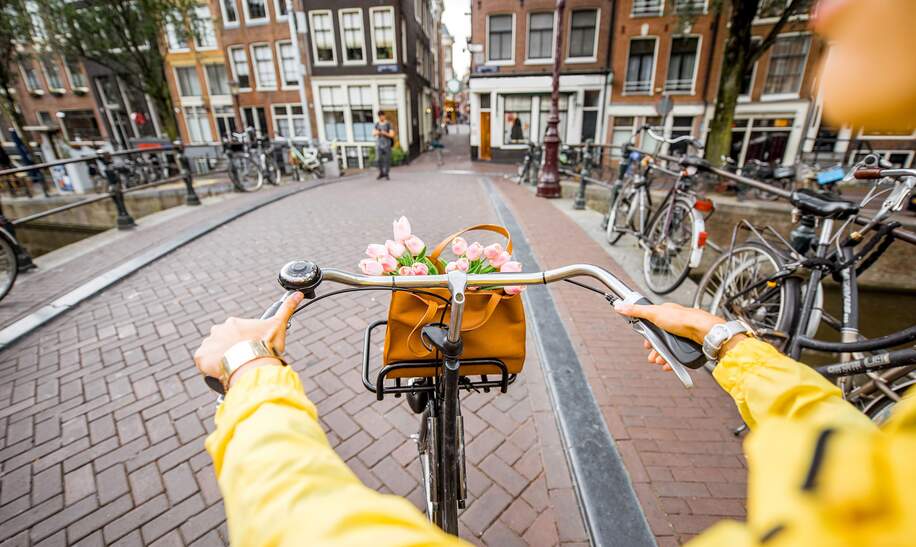 eine Person, die mit einem Fahrrad durch eine Strasse in Amsterdam faehrt | ©  Gettyimages.com/RossHelen